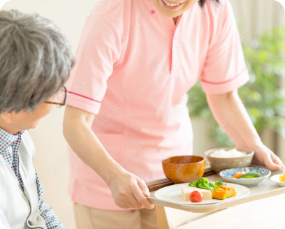 介護士が介護施設の食堂で入居者に食事を配膳している様子